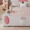 A child's bed with a unicorn theme, featuring a stuffed unicorn, pink bedding, and a bedside table. Produktbild-Vorschau