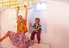 Two children are playing in a room with a yellow climbing bar. One child is hanging from the bar, and the other is sitting in a window niche. Produktbild-Vorschau