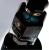 A close-up shot of a black perfume bottle with gold accents. Voir les images du produit