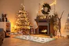 A cozy living room decorated for Christmas, featuring a decorated Christmas tree, a fireplace with stockings, and festive decor. Podgląd zdjęcia produktu