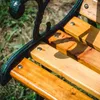 Close-up of a wooden park bench with black metal frame. Podgląd zdjęcia produktu