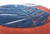 Close-up of a textured fabric with a blue leaf-like pattern on an orange background. Podgląd zdjęcia produktu