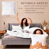 Two women in bed with pillows and bedding, one stretching and the other holding a pillow. Produktbild-Vorschau