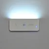 A white LED night light with a motion sensor is mounted on a light gray wall, emitting a bright white light upwards. Produktbild-Vorschau