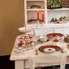 A festive Christmas table setting with a tiered cake stand, cupcakes, and other decorative items. Anteprima dell’immagine prodotto