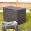 A dark gray storage box sits on a grassy lawn next to a toolbox. Podgląd zdjęcia produktu