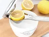 A close-up shot of a manual citrus juicer with a lemon half being squeezed into a white bowl. Produktbild-Vorschau
