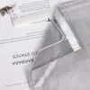 A close-up view of a gray sheer curtain with a white velcro strip and a drawstring, layered over pages of text. Produktbild-Vorschau