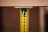 A close-up view of a yellow tape measure hanging from a wooden surface. Voir les images du produit