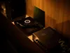 A turntable, amplifier, and speaker are set up on a shelf against a wooden wall. Produktbild-Vorschau