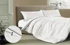 A neatly made bed with white bedding and navy blue trim, featuring a close-up inset of the bedding's button closure. Produktbild-Vorschau