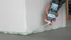 A hand is using a can of expanding foam to seal the base of a large white block, likely for insulation or construction. Produktbild-Vorschau