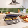 A kitchen counter with a sandwich maker, sandwiches, and vegetables. Voir les images du produit