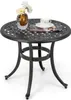 A round, dark brown cast aluminum side table with a decorative top and three curved legs, set against a white background. A glass vase with white flowers and a book with a coffee cup on top are placed on the table. Podgląd zdjęcia produktu