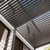 A close-up view of a modern pergola with a slatted roof, attached to a building with large windows. The sky is visible through the slats. Voir les images du produit