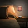 A bedside table with a lamp next to a bed. Náhled obrázku produktu