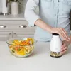 A person is using a manual food chopper next to a bowl of spiralized vegetables. Produktbild-Vorschau