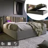 A bedroom scene featuring a modern upholstered bed with a tufted headboard and integrated lighting. An inset image shows the bed's storage compartment. Produktbild-Vorschau