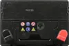 The top view of a black car battery with various safety symbols and a green indicator light. Náhled obrázku produktu