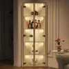 A tall, narrow glass display cabinet with LED lighting, showcasing various decorative items and bottles on its shelves. The cabinet is positioned in a room with soft lighting and decorative elements in the background. Produktbild-Vorschau