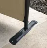 Close-up of the base of a tan fabric screen attached to a black metal pole, resting on a tiled patio. Produktbild-Vorschau