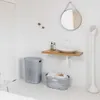 A modern bathroom with a sink, mirror, laundry basket, and a tall white appliance. Náhľad obrázku produktu