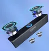 A 3D render of a black computer soundbar with two speakers shown above it, against a light blue background. Voir les images du produit