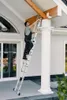A man is using a ladder to work on the exterior of a house, near a white column and a window. Produktbild-Vorschau