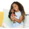 A young girl is holding a doll and smiling. Voir les images du produit