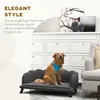 A golden retriever dog sits on a dark gray dog couch in a living room setting, with a white cabinet and artwork in the background. Náhled obrázku produktu