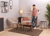A woman is vacuuming a living room with a cordless vacuum cleaner. Voir les images du produit