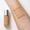 A bottle of Artdeco Rich Treatment Foundation is shown next to an arm with several swatches of foundation shades. Náhled obrázku produktu