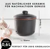 A dark gray ceramic garlic pot with a lid, placed on a light-colored surface, with several garlic bulbs in the foreground. Produktbild-Vorschau
