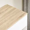 Close-up of the top corner of a white cabinet with a wood-grain effect top surface. A grey curtain is visible in the background. Podgląd zdjęcia produktu