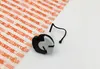 A STIHL oil tank cap is placed on a white surface next to a sheet of packaging material with the STIHL logo repeated on it. Produktbild-Vorschau