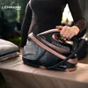 A person is holding a steam iron station on an ironing board, with folded clothes nearby. Produktbild-Vorschau