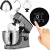 A hand is shown pressing a button on the digital display of a ZEEGMA kitchen mixer. The mixer is gray and silver, with a stainless steel bowl. Several attachments are visible above the mixer. Náhľad obrázku produktu
