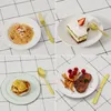 A collage of four different food dishes, each with gold cutlery, set on a white and black checkered tablecloth. Produktbild-Vorschau