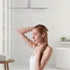 A woman is showering under a large square shower head. Produktbild-Vorschau