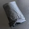 A black grill cover is shown lying on a gray surface. Náhľad obrázku produktu