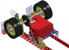 A close-up, 3D rendered view of a mechanical assembly with gears, wheels, and a red motor unit, set against a white background. Podgląd zdjęcia produktu