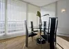 A dining room with vertical blinds and a glass-top dining table with chairs. Produktbild-Vorschau