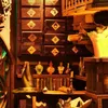 A collection of items that appear to be part of a miniature model or diorama, possibly a wizard's study or laboratory, with various boxes, bottles, books, and a hat. Voir les images du produit