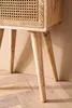 A close-up shot of the legs and lower part of a wooden nightstand with a rattan front. Produktbild-Vorschau