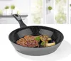 A frying pan with food inside, set against a kitchen background. Produktbild-Vorschau