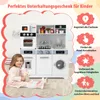 A young girl sits on the floor in front of a toy kitchen set, holding a stuffed bunny. The toy kitchen is white and gray and includes various appliances like a microwave, oven, and washing machine. The background is a white cloud shape with red borders. Te Náhled obrázku produktu