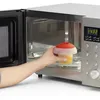 A hand places a food container into a microwave. Podgląd zdjęcia produktu