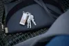 A set of keys with a small flashlight attached, resting on a dark handbag. Anteprima dell’immagine prodotto