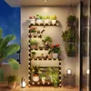 A balcony with a plant stand decorated with fairy lights, showcasing various potted plants. Voir les images du produit