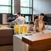 A family is preparing pasta in a modern kitchen. The product, a pasta drying rack, is visible in the foreground, holding fresh pasta. Produktbild-Vorschau